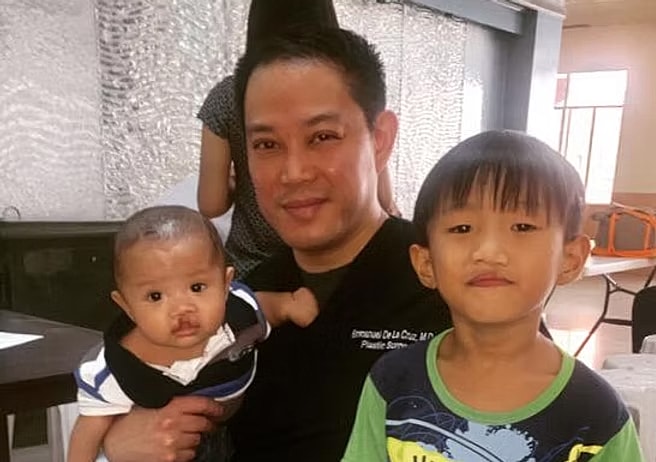 Man holding baby with young boy nearby.