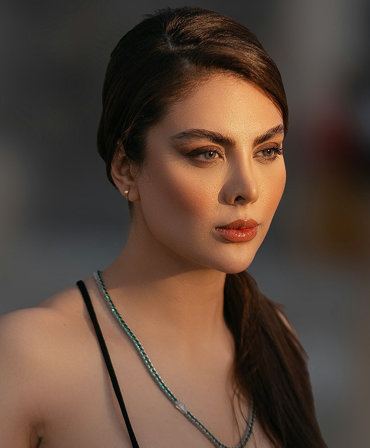 Woman with elegant makeup and jewelry in sunlight.