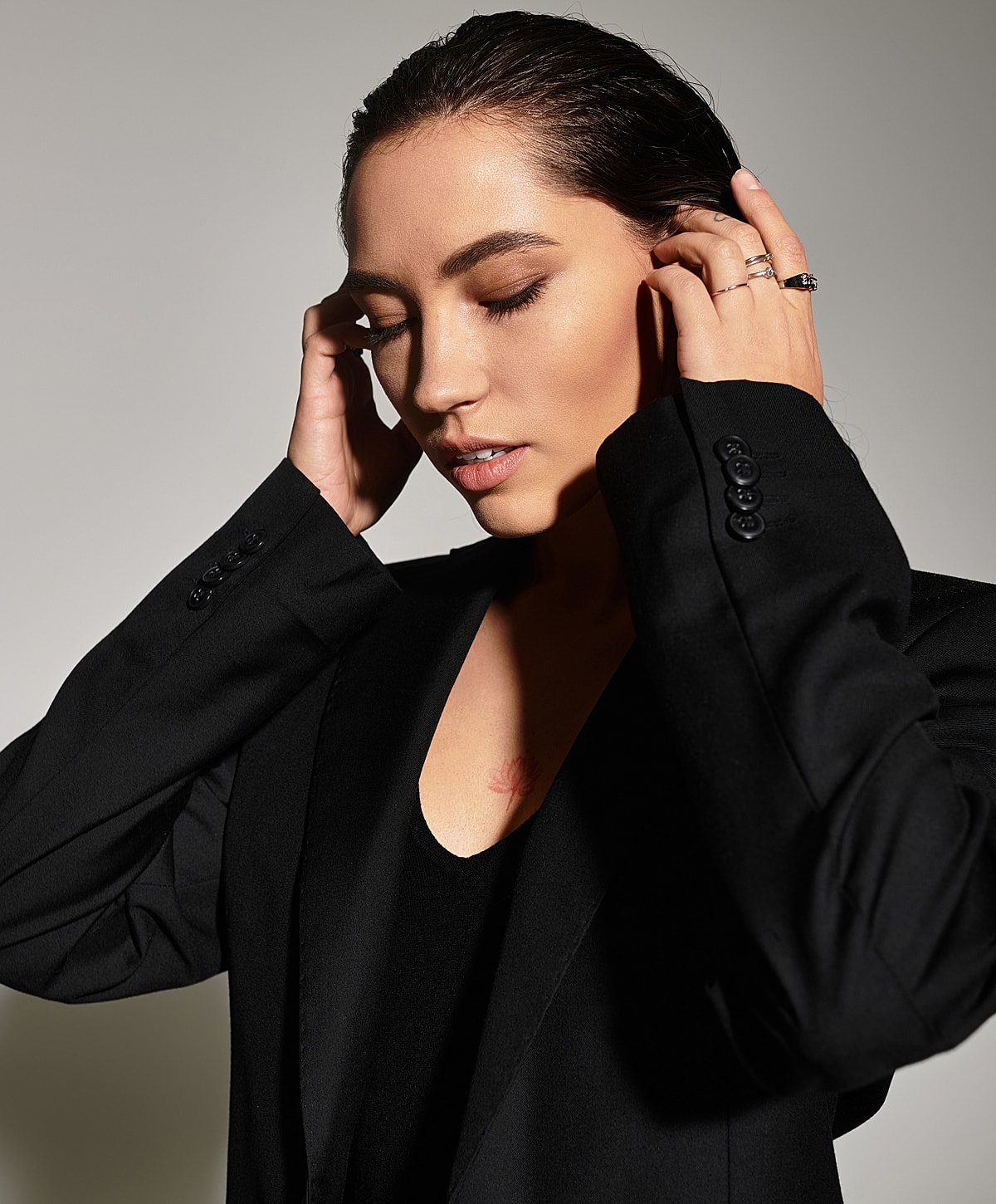 Woman in black blazer touching her hair.