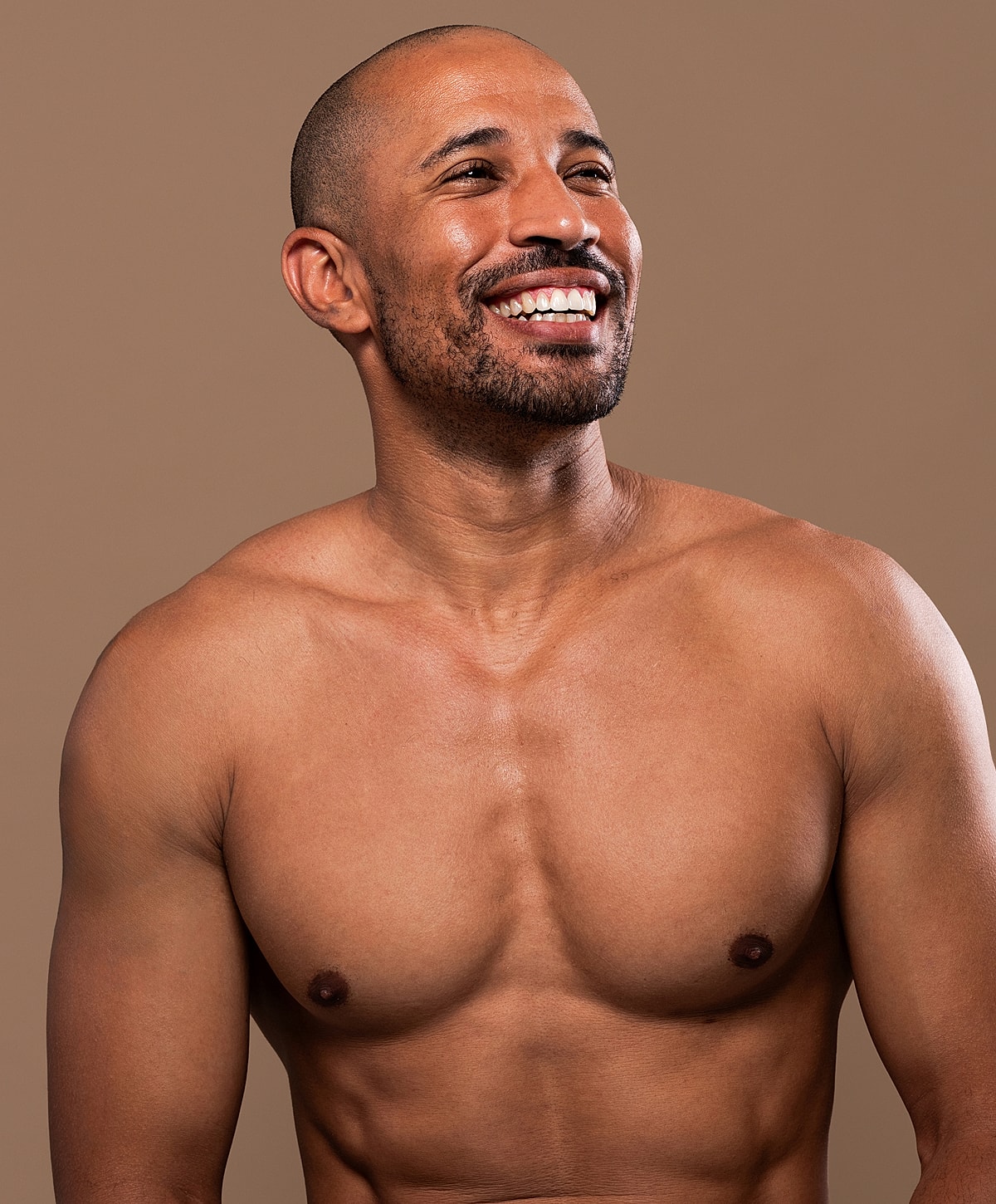 Smiling man with a muscular physique and shaved head