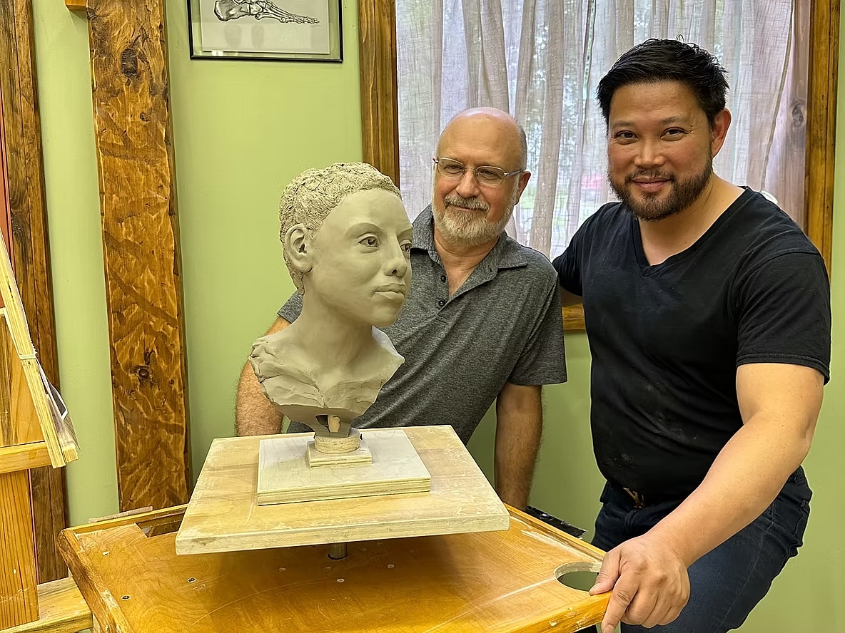 Artists with a clay sculpture in studio.