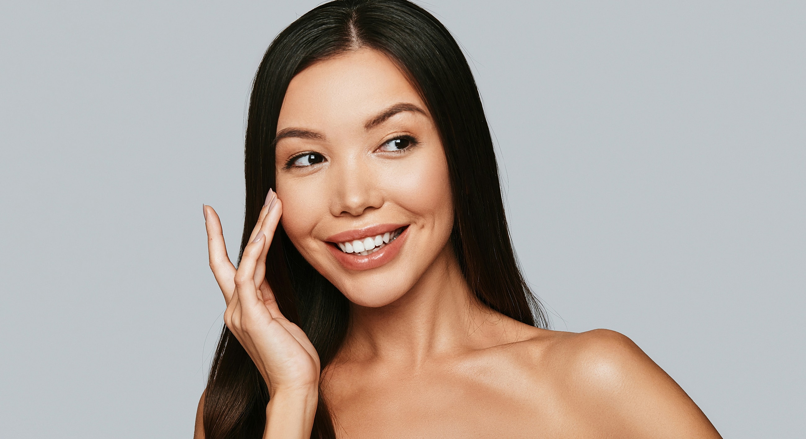 Smiling woman with long hair and clear skin.