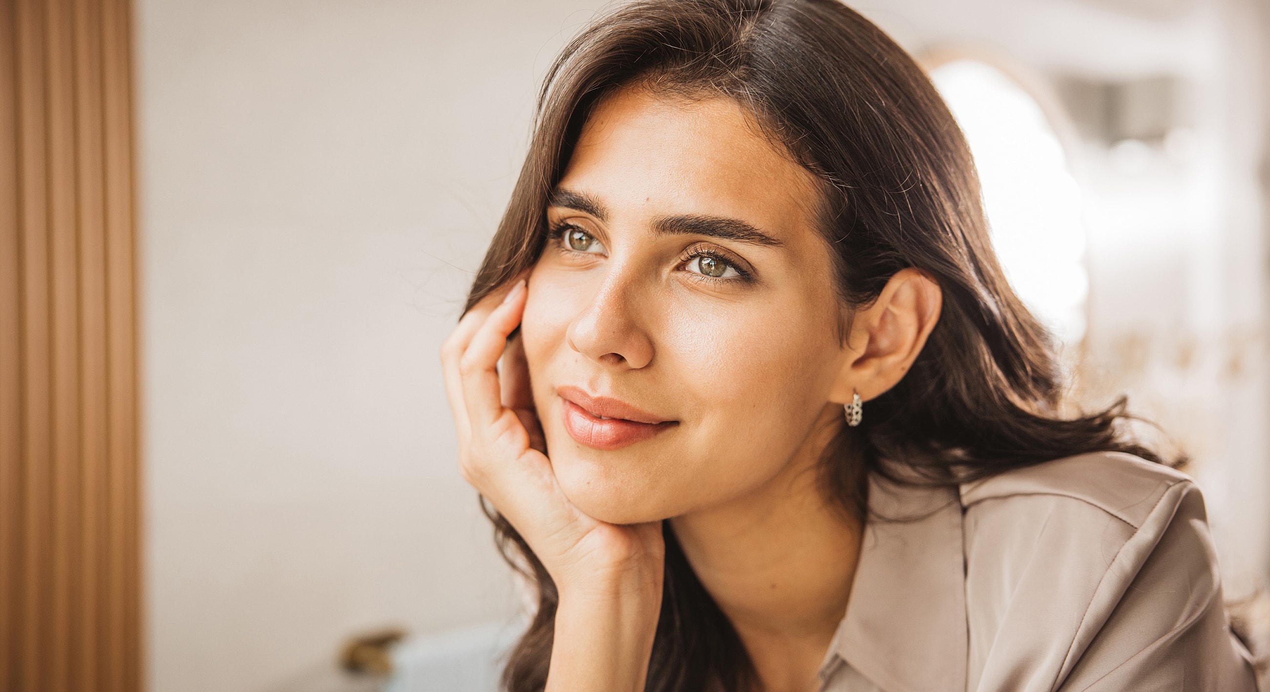 Thoughtful woman with natural makeup and earrings.