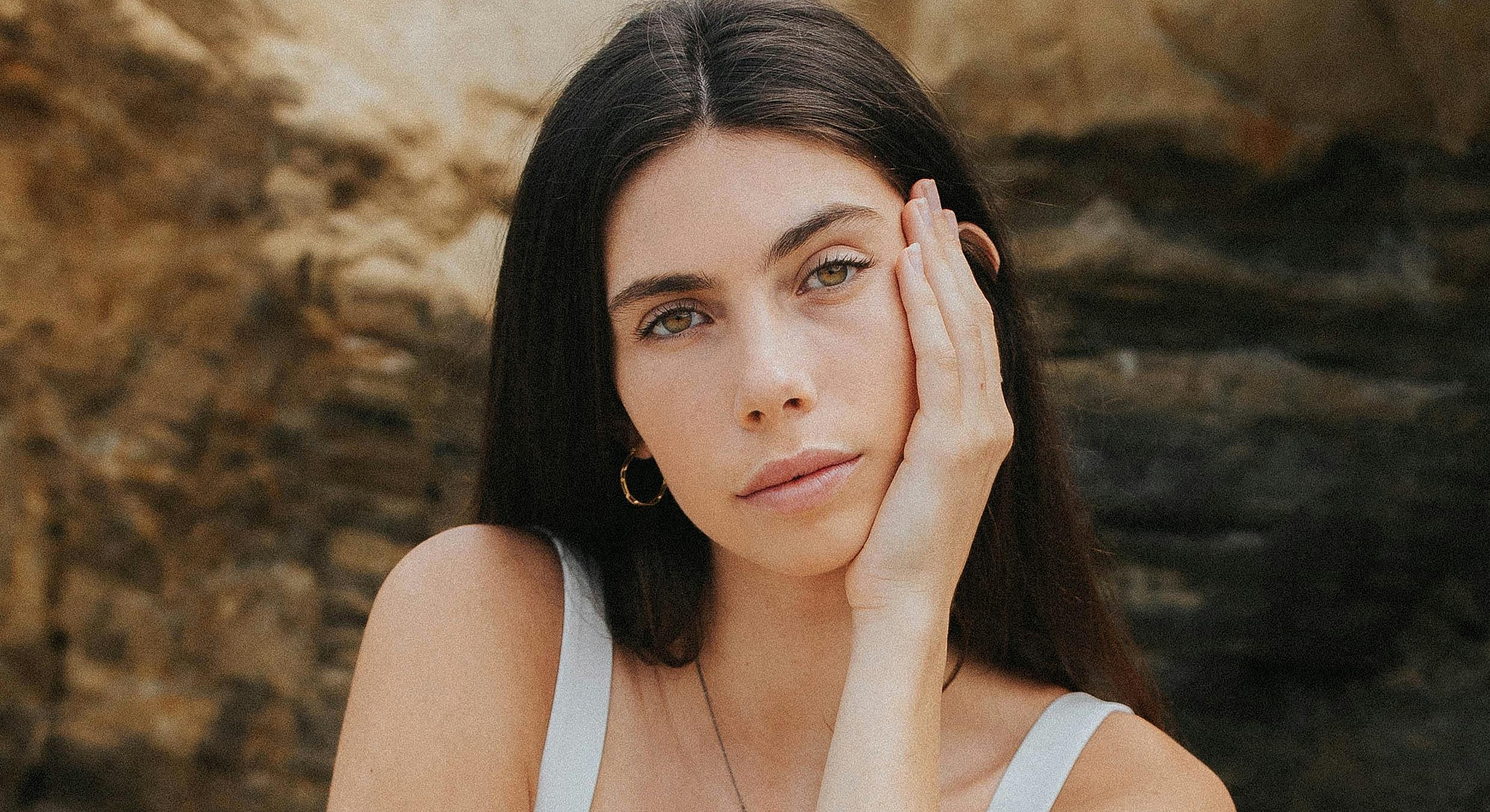 Woman resting her face on her hand outdoors.