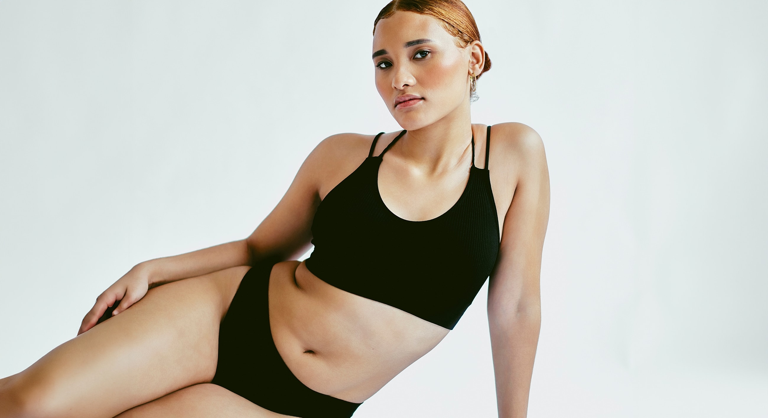Model in black sportswear against a neutral background.