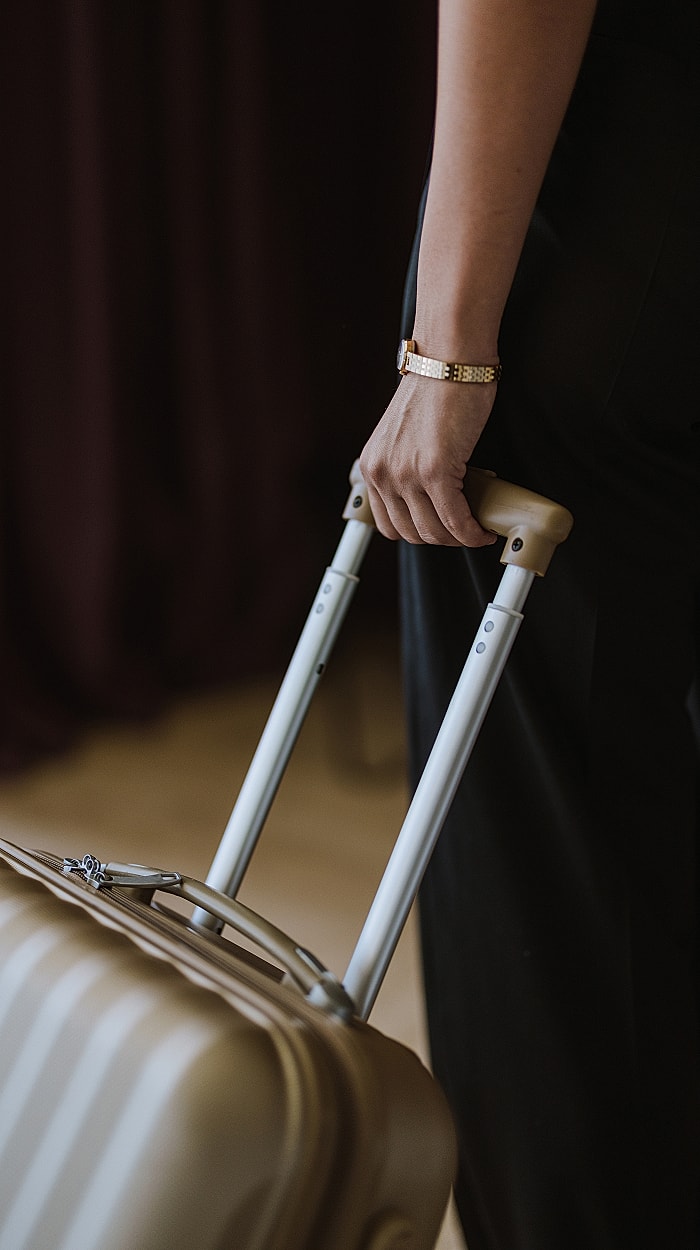 Person holding a suitcase with stylish watch.